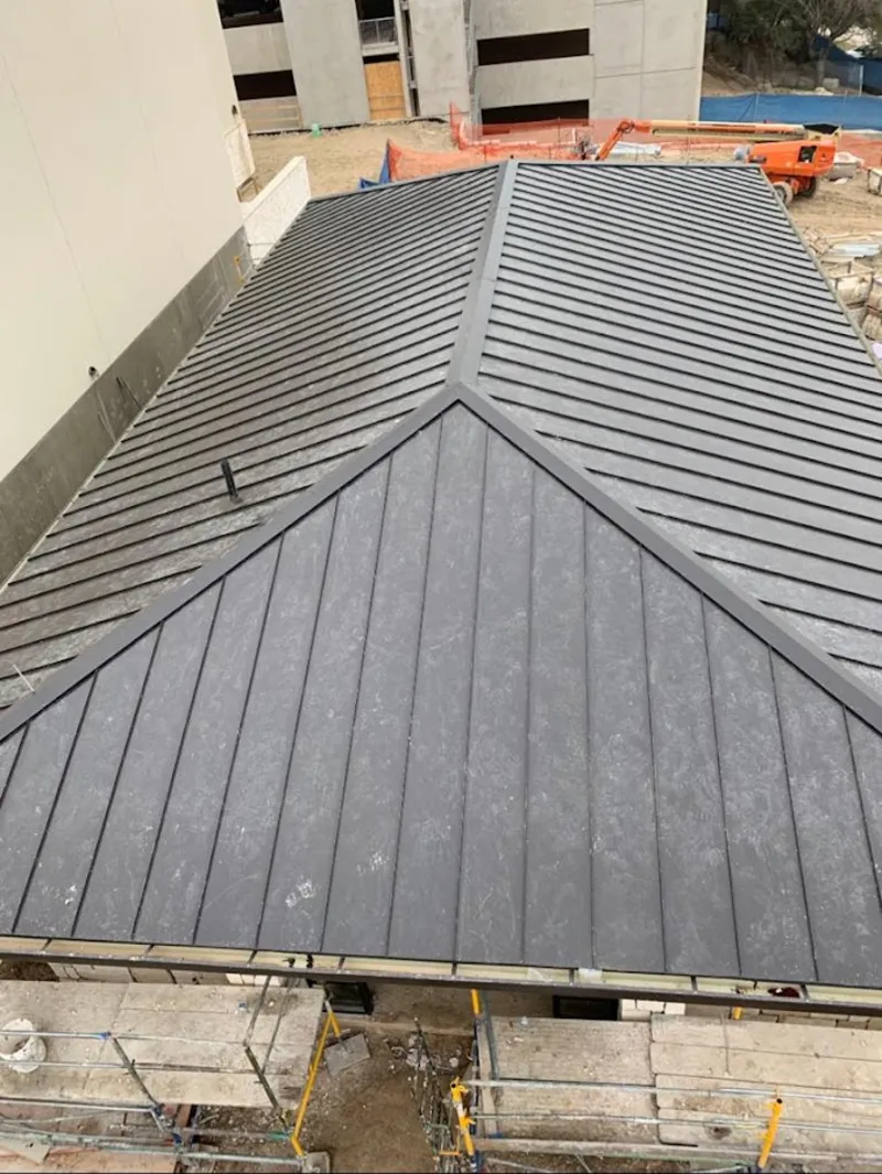Commercial metal roof construction with crane equipment in Aurora
